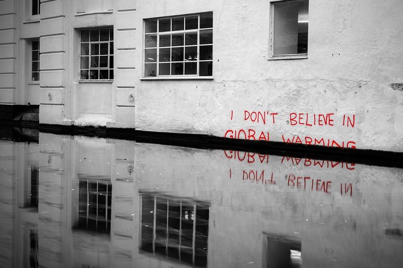 'I don't believe in climate change' is written in red on a wall