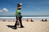 A souvenir vendor walks along Kuta beach, Bali