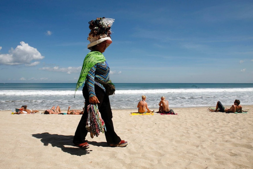 A woman selling souvenirs walks through Kuta beach at the Indonesia's resort island of Bali.