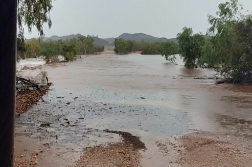 a flooded river with trees and hills in the background.