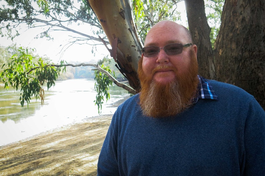 Rene Woods stands on the river bank above the Murray river.