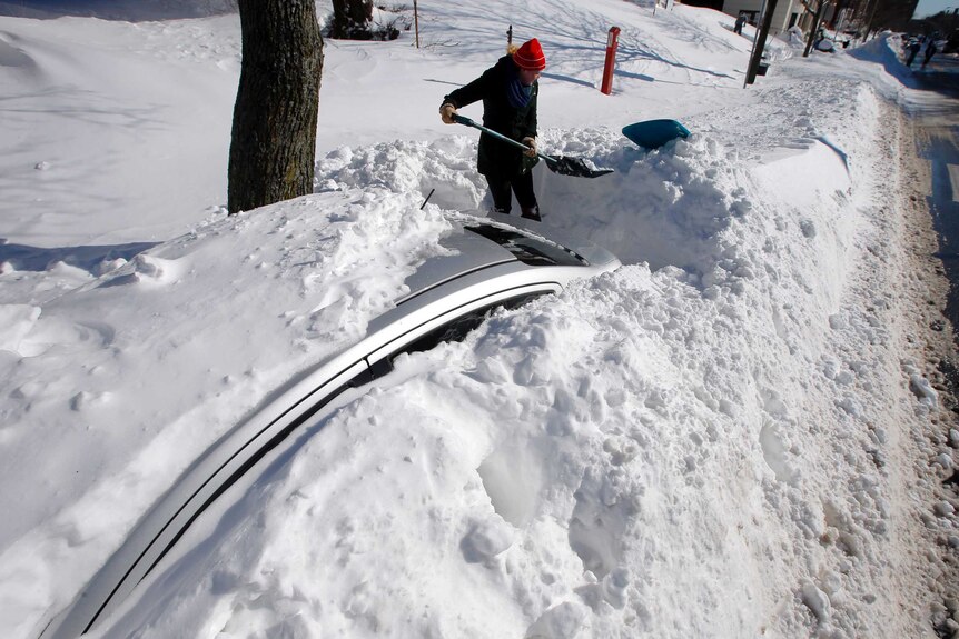 Woman digs car out of snow