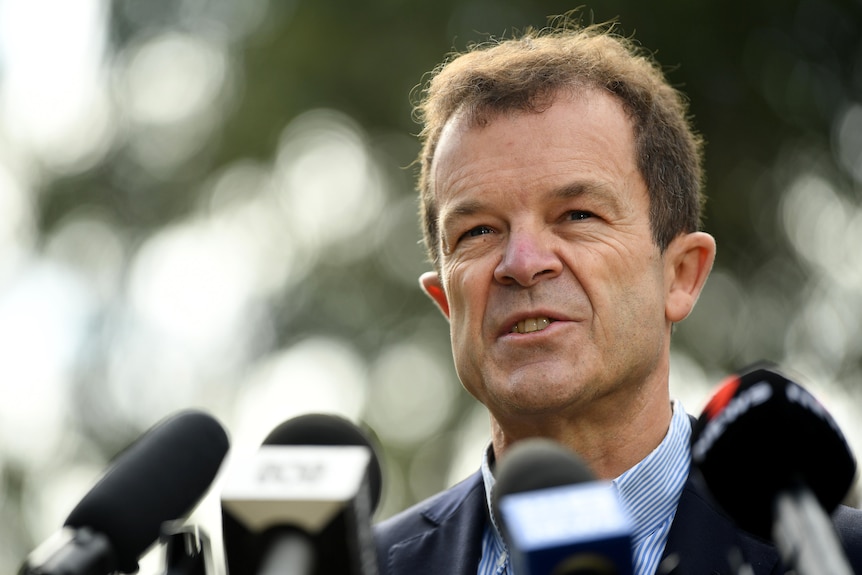 a man speaking into microphones at a press conference