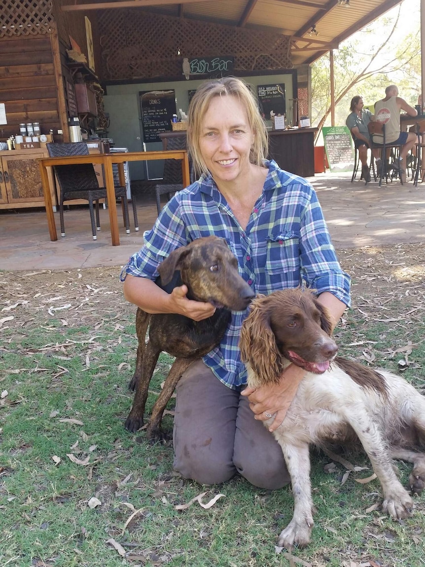 Holding onto two dogs is scientist Dr Sarah Legg at Mornington research station in the Kimberley