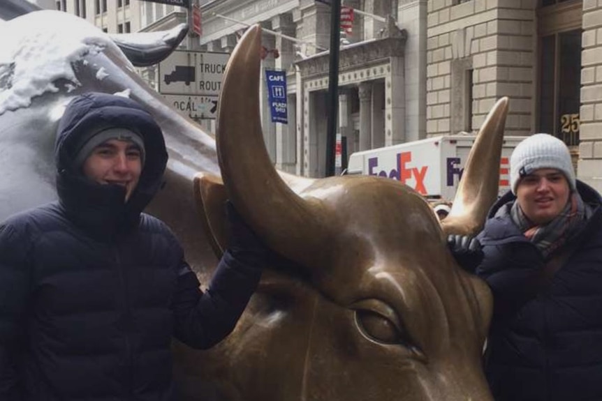Gregory and Christopher Loukaitis standing next to bronze bull sculpture.