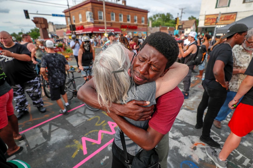 A white woman and a black man embrace amid Juneteenth demonstrations.