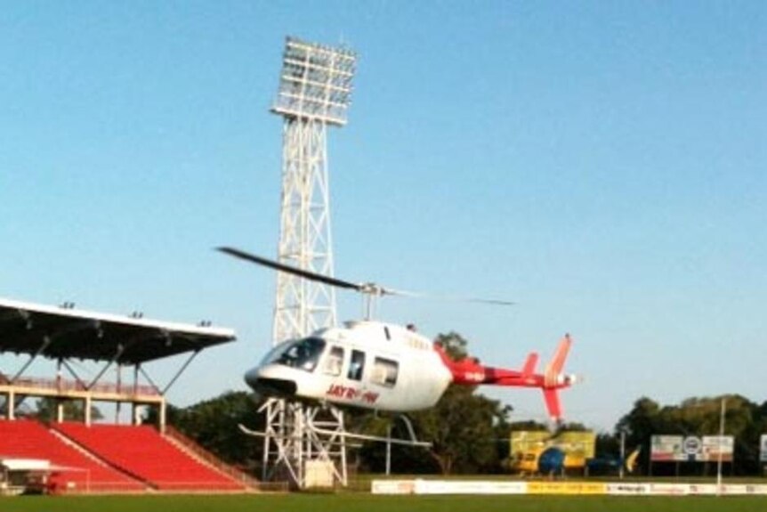 A helicopter hovers over Marrara Oval in Darwin in an attempt to dry it