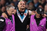 Sam Powell-Pepper grimaces as club doctors help him from the field