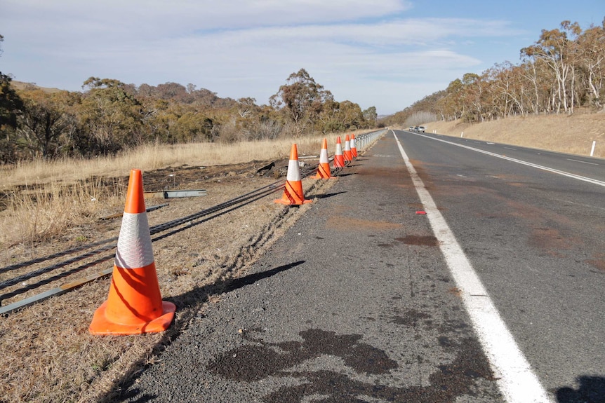 Traffic cones line the side of a highway where a barrier has been taken out.