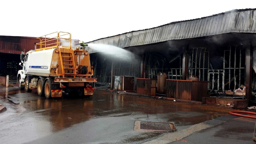 A fire truck blasts a stream of water into a blackened building.