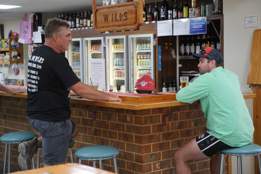 Two men talk at a bar