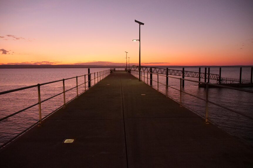 A jetty stretches towards the sunset