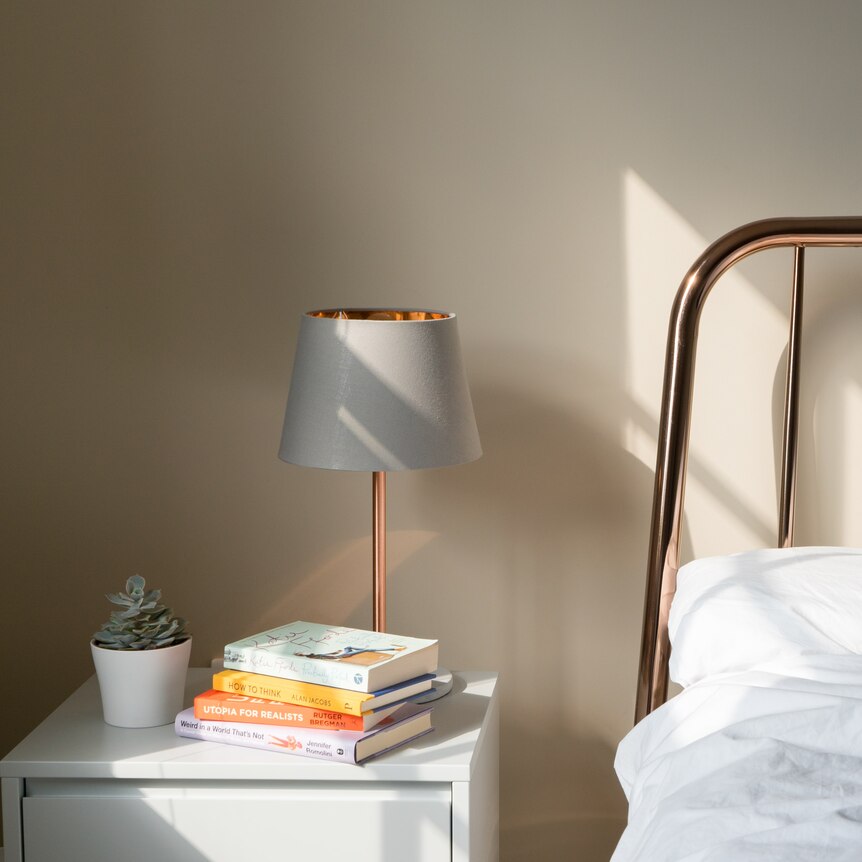 bedside table with books and lamp next to bed