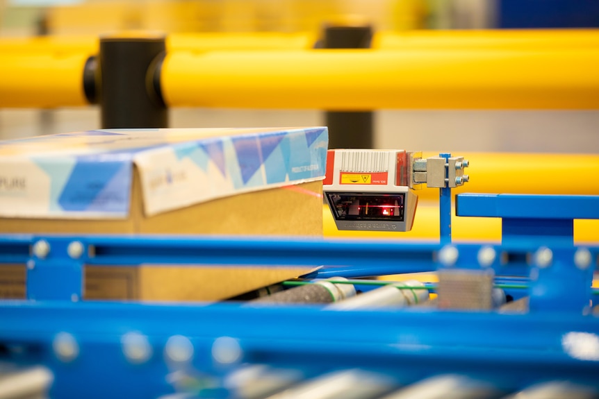 A meat box is passing by a high-tech camera on a production line.