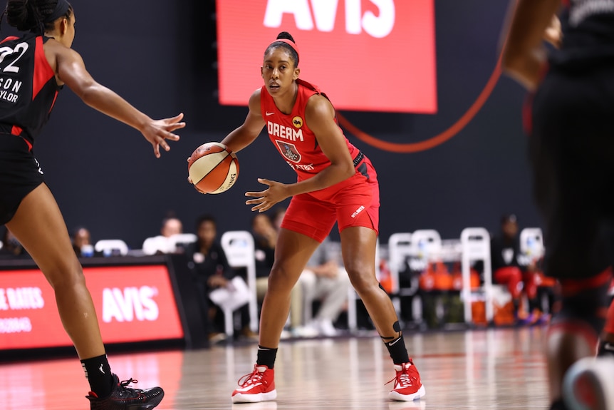 WNBA player dribbles the ball during a match with opposition player defending her