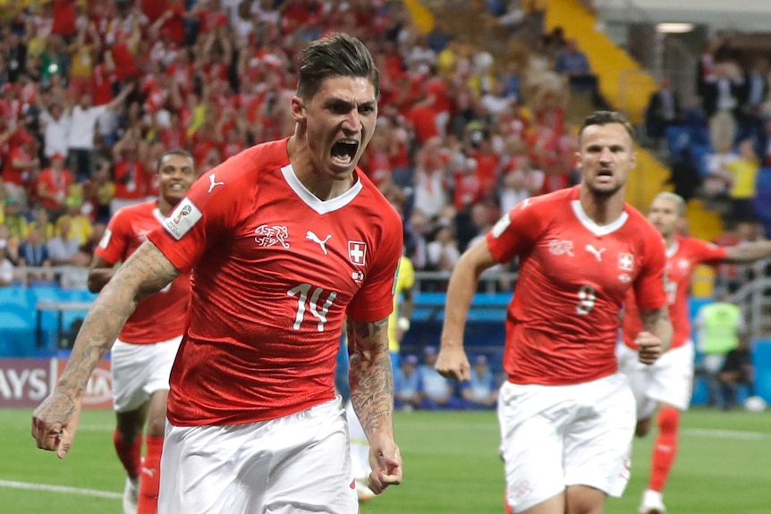 Swiss striker roars with delight while being chased by teammates after scoring goal