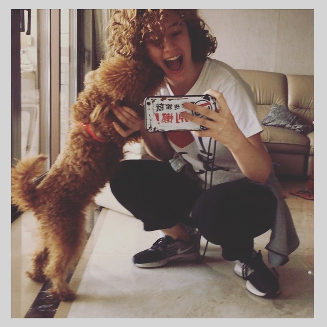 A young woman pats a dog as she takes a selfie with a mobile phone