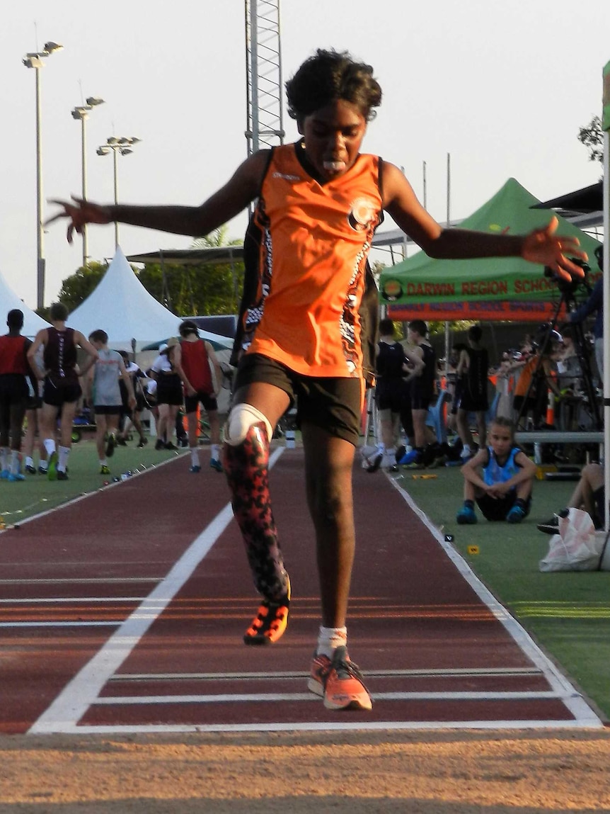 one legged girl jumping with hands in air