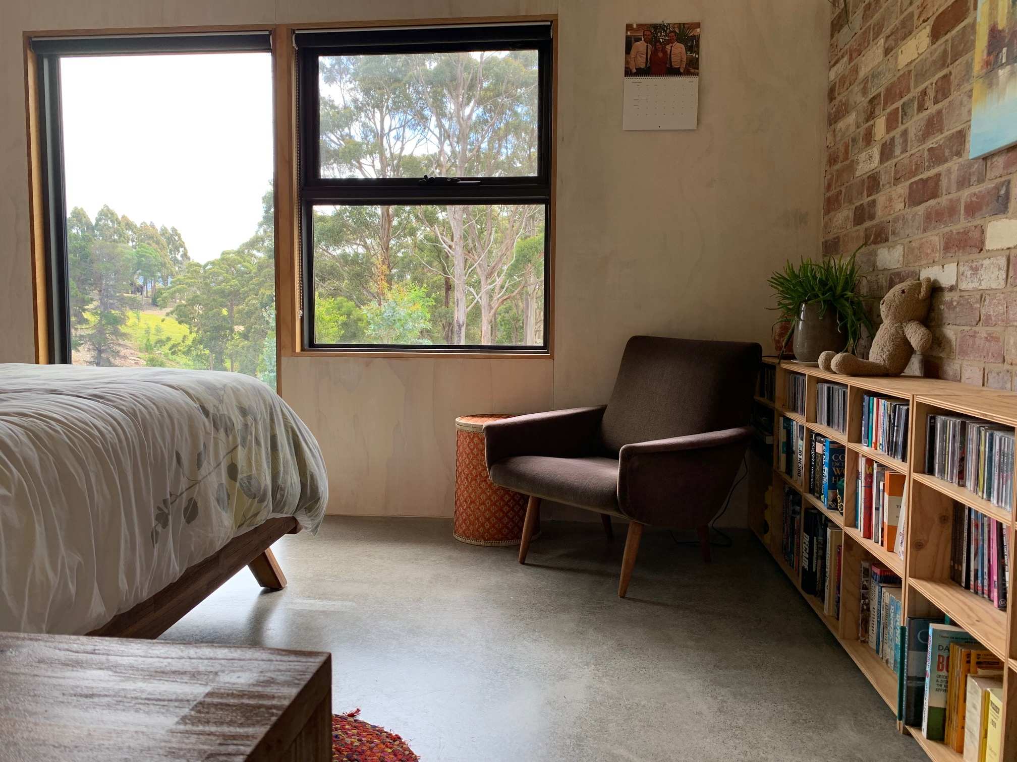 A bedroom with bookshelves on the left side of the photo, and the edge of the bed in the right