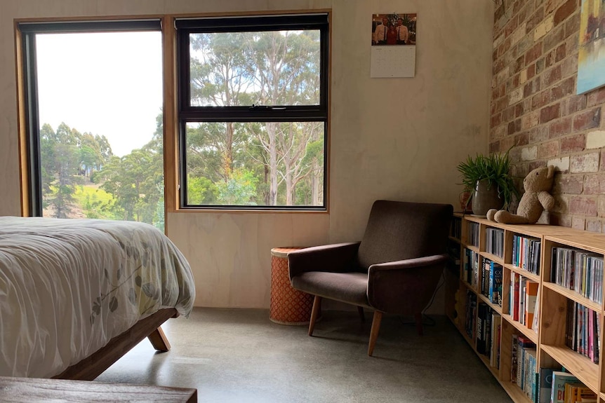 A bedroom with bookshelves on the left side of the photo, and the edge of the bed in the right