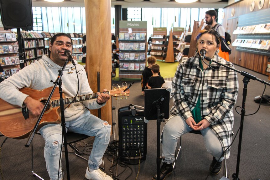 A man plays guitar and sings while a woman sings