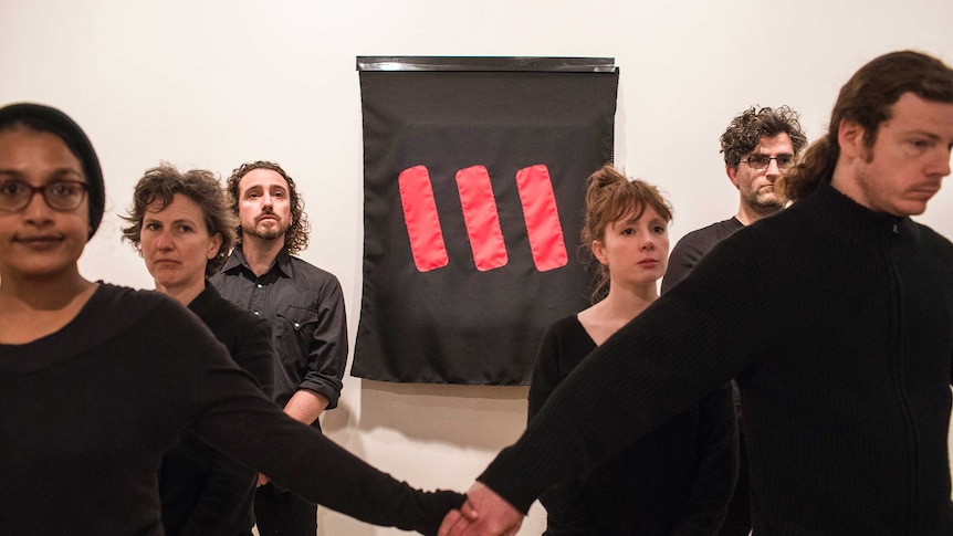 Protesters stand next to Picasso's Weeping Woman after covering it with a black cloth.