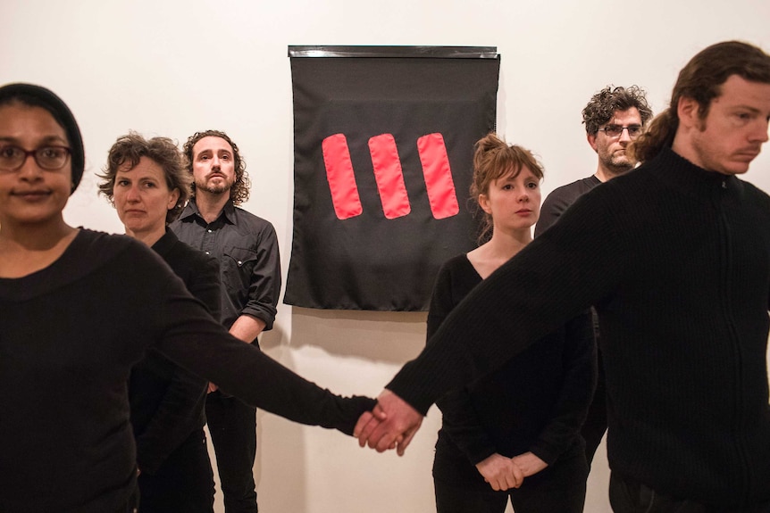 Protesters stand next to Picasso's Weeping Woman after covering it with a black cloth.