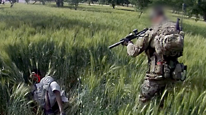 SAS soldier points gun at Afghan man