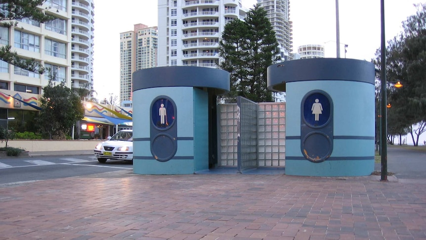 A mid-century style bus stop in two shades of blue with large male and female toilet symbols on the front.