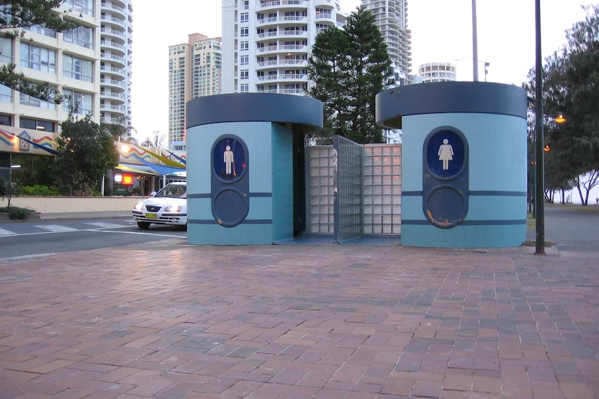 A mid-century style bus stop in two shades of blue with large male and female toilet symbols on the front.