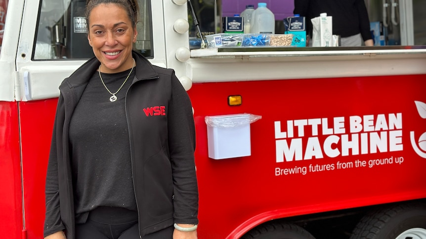 lady with hair tied back wearing black standing in front of red coffee truck with servingcounter