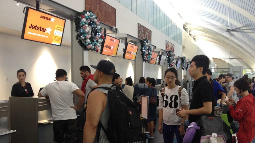 Jetstar passengers at Darwin Airport queue to check-in after being stranded overnight.