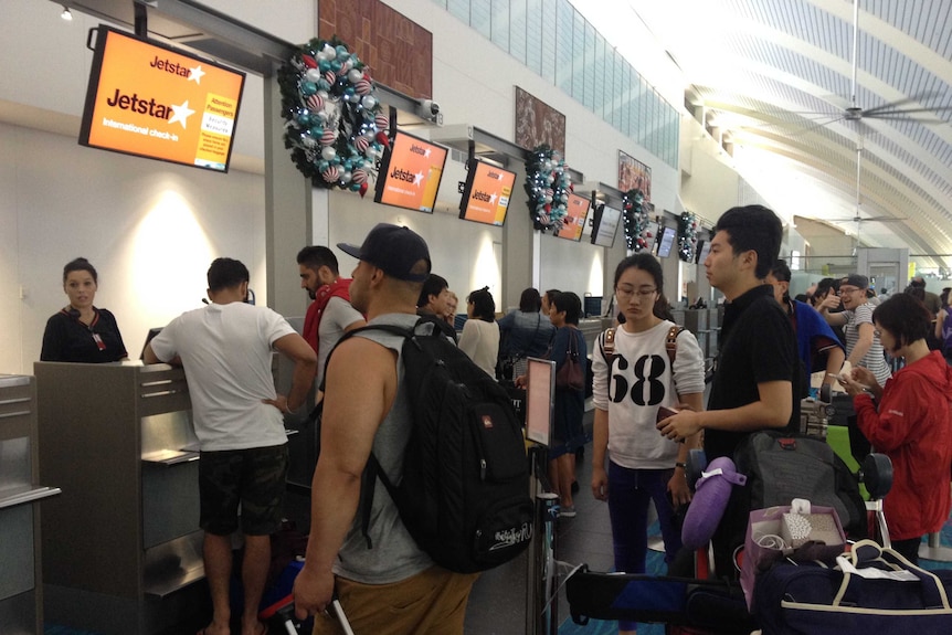 Jetstar passengers at Darwin Airport queue to check-in after being stranded overnight.