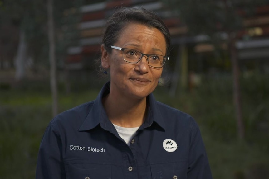 A woman in a blue CSIRO shirt looks at past the camera.