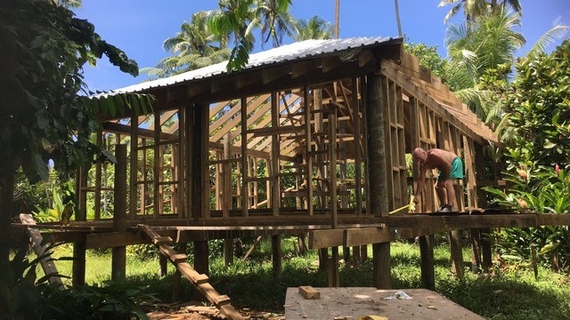 A man is working on the framework of a house.
