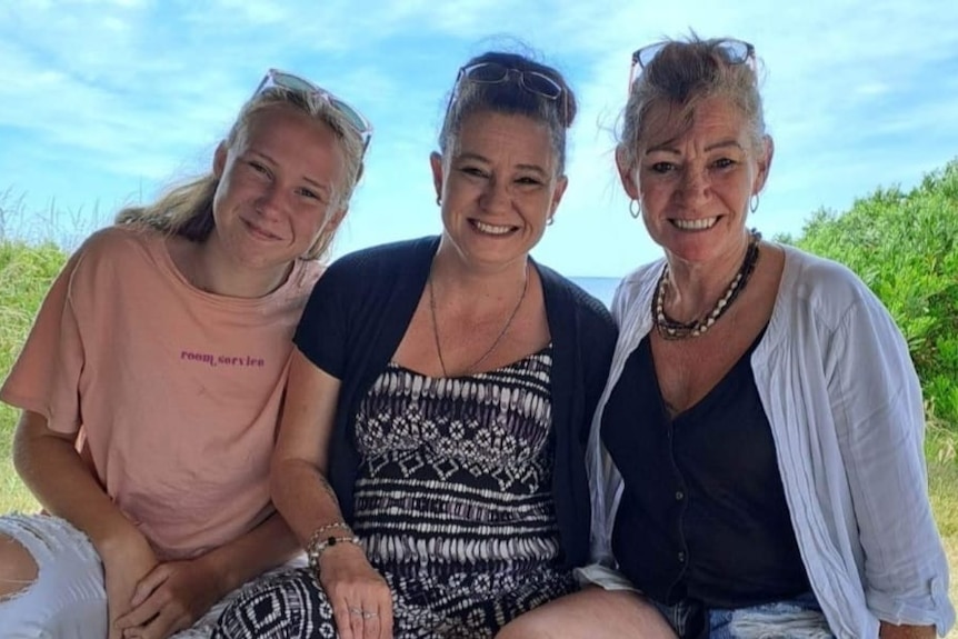 Three woman sit together smiling