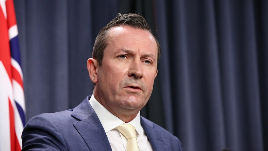 A head and shoulders shot of Mark McGowan speaking during a media conference indoors.