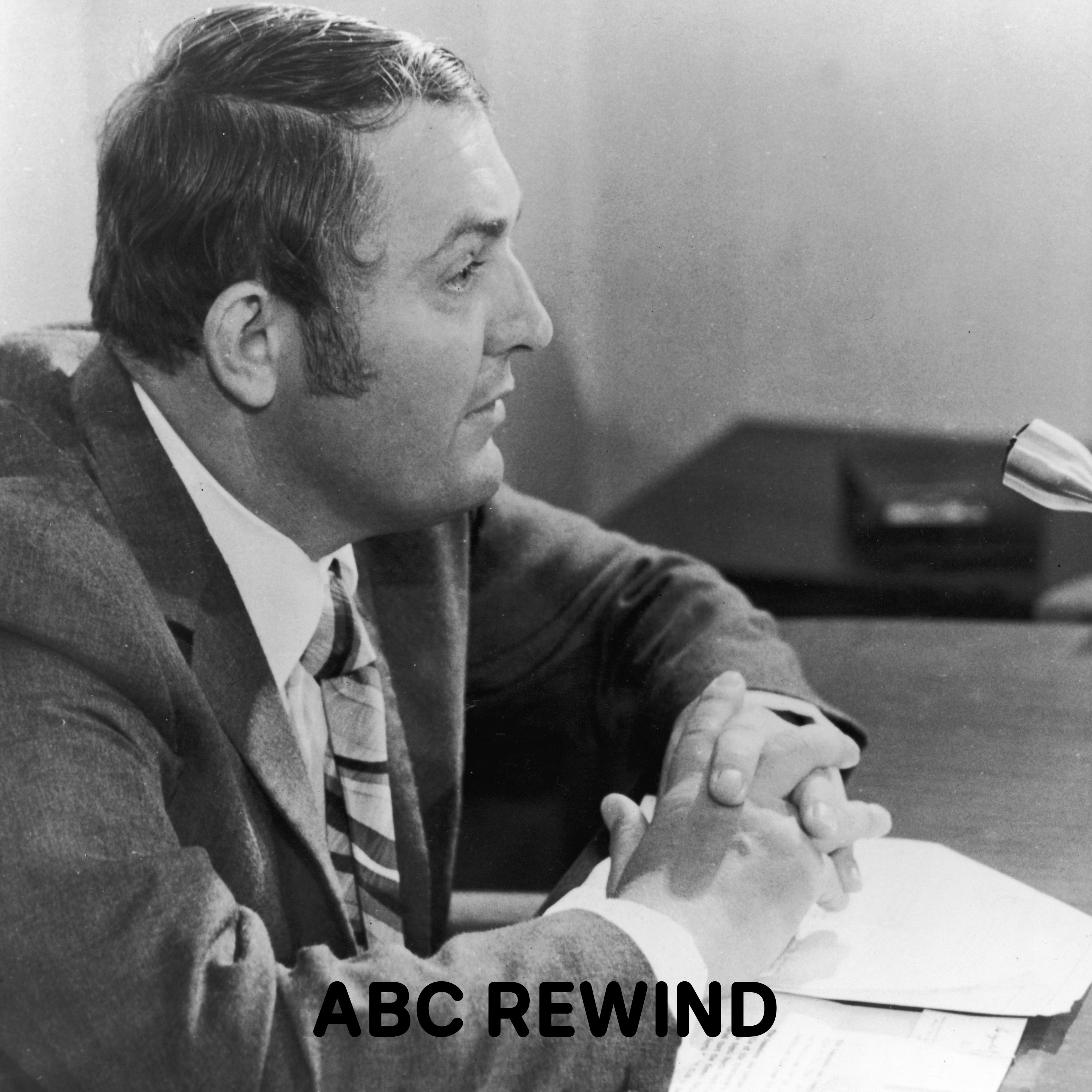 Black and white profile photo of Alan Bond in a suit with his hands clasped on a desk.