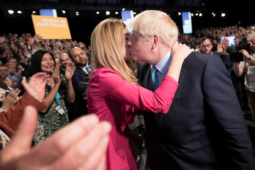 Boris Johnson kisses Carrie Symonds in front of a cheering crowd.