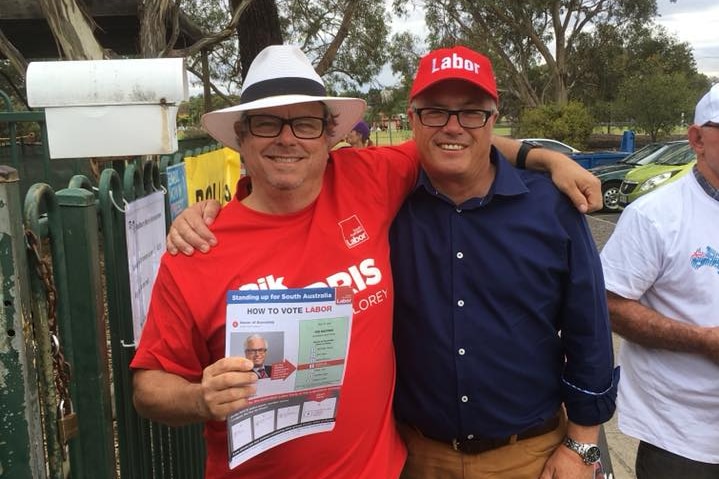 A smiling man wearing a red Labor shirt poses for the camera with Rik Morris.