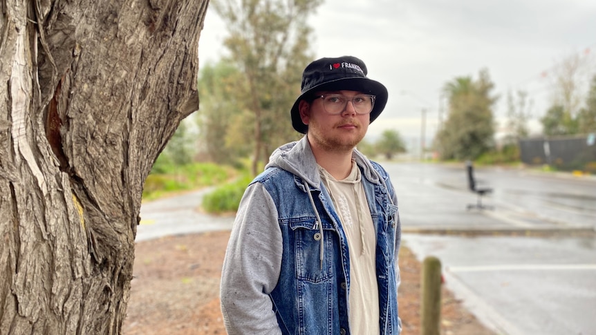 A man in a black hat standing near a road