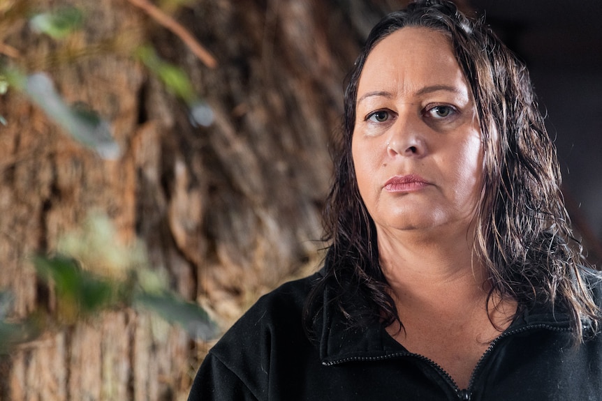 An Indigenous woman looking determined standing in front of a tree in an artwork at Dark Mofo