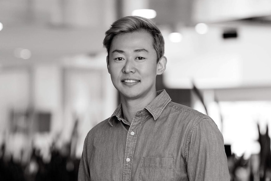 A black and white portait of a young man standing in a building.