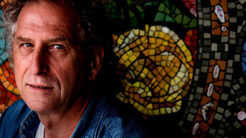 A man in front of a glass mosaic.