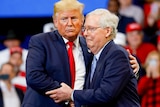 Donald Trump with his arms around Mitch McConnell at a rally