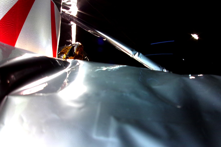 A close up of the damaged surface of a spacecraft as it floats through space.