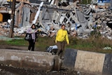 Local residents walk past a building, that was destroyed during the fighting in Bakhmut.