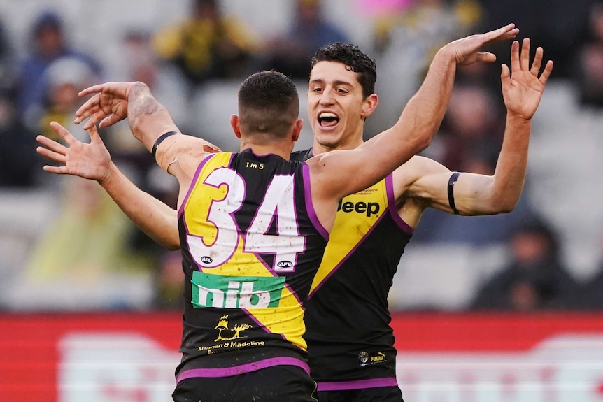 Jason Castagna high-tens Jack Graham, who has his back to the camera.