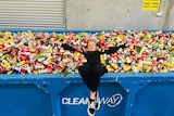 Lady laying in a skip filled with beer cans.