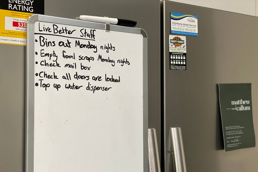 A whiteboard on a fridge with tasks listed, including bins and emptying food scraps.